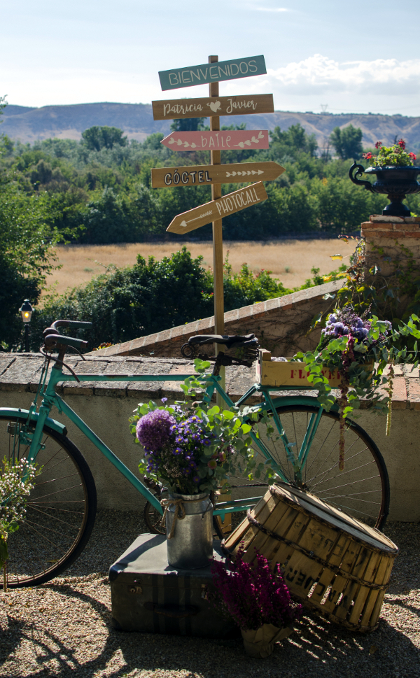 Decoración de boda con bicicleta, carro y cajas con flores