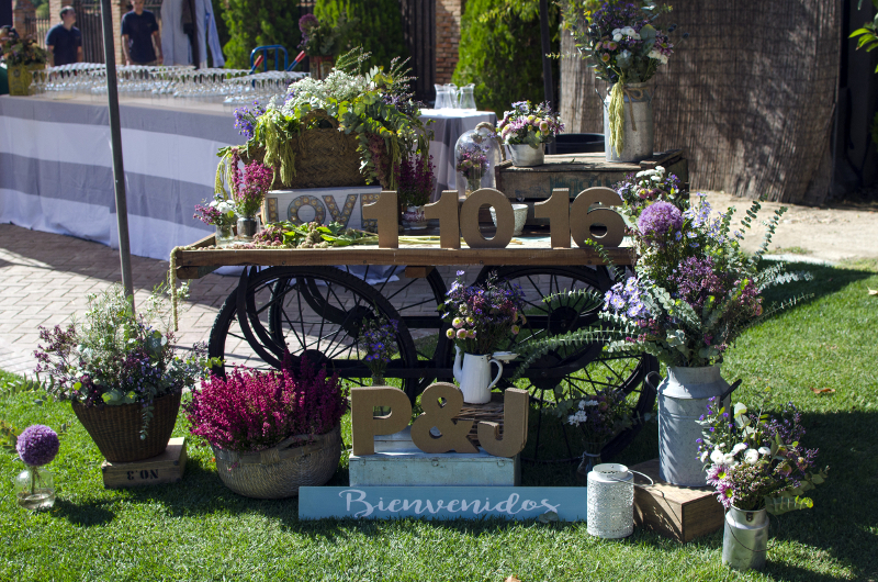 Decoración de boda con bicicleta, carro y cajas con flores