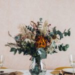 Centro de flores preservadas en jarrón de cristal con base de madera