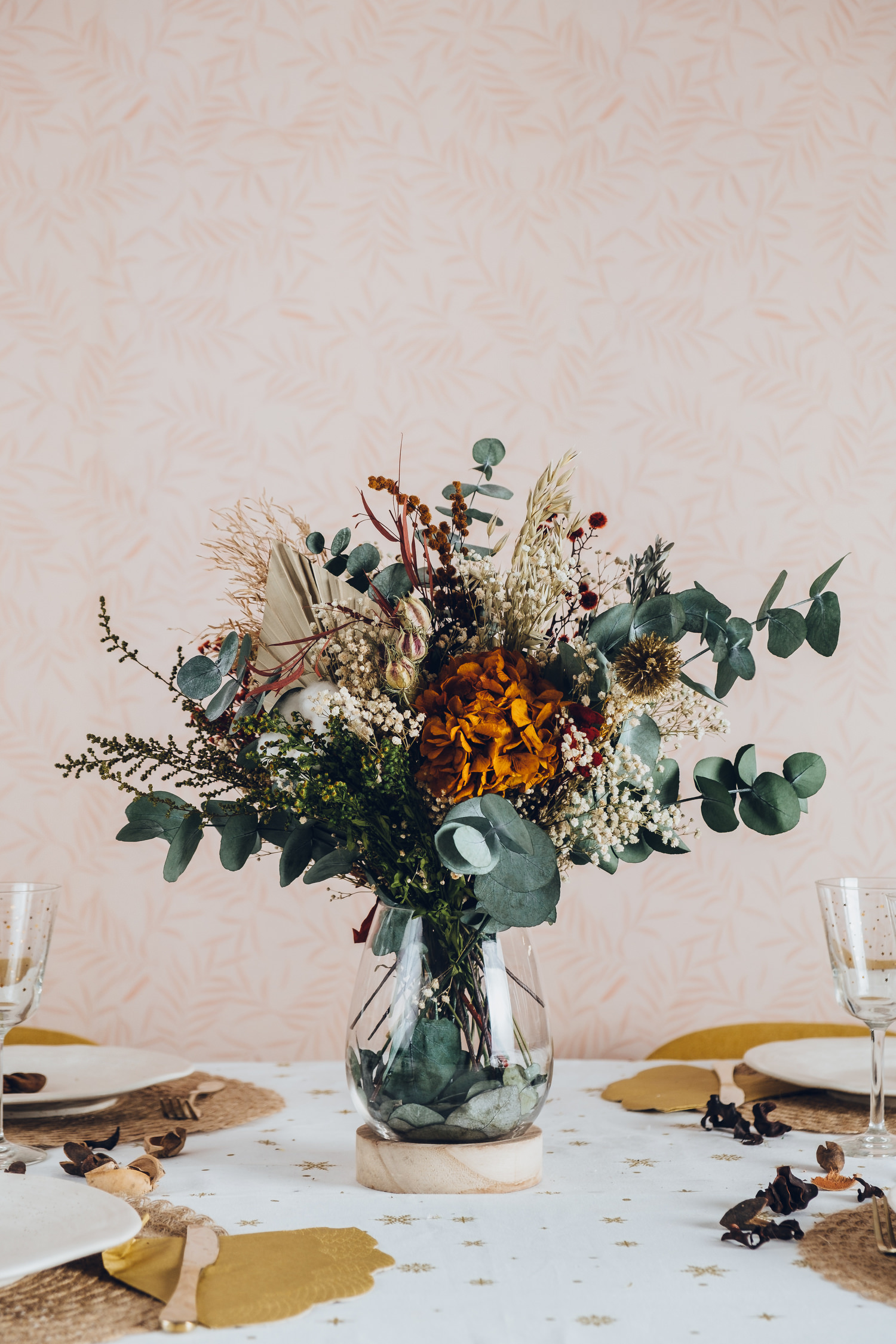 Centro de flores preservadas en jarrón de cristal con base de madera
