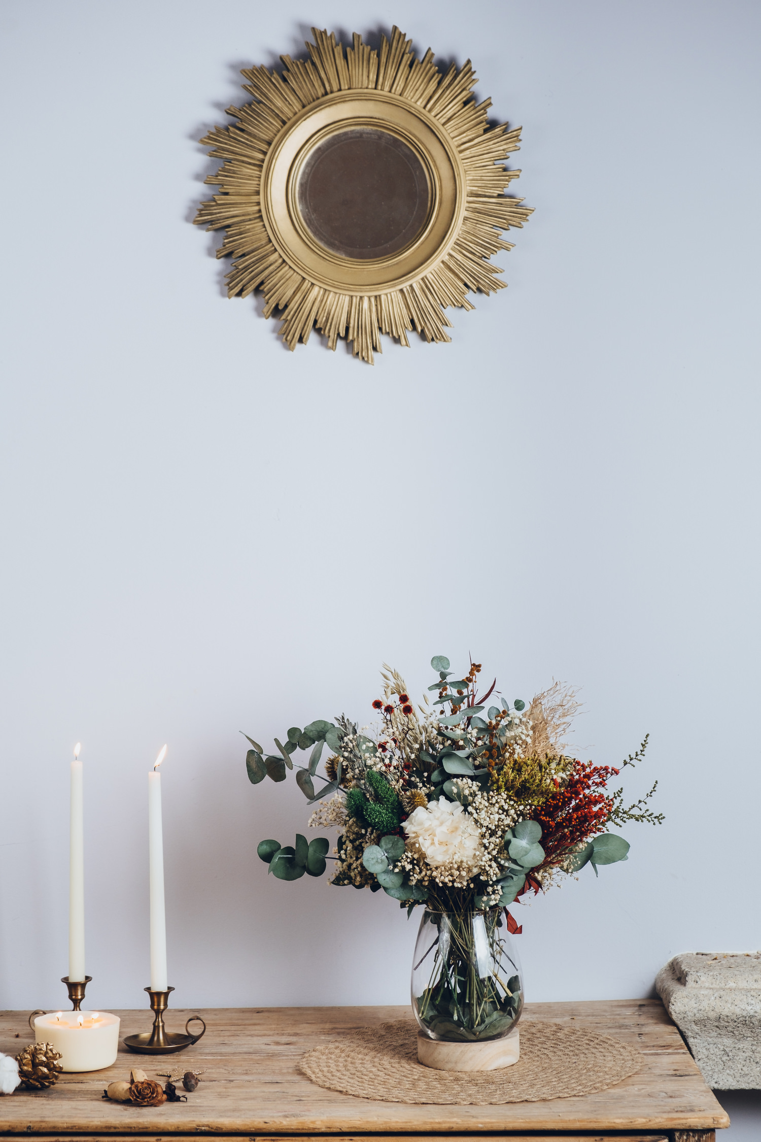 Centro de flores preservadas en jarrón de cristal con base de madera