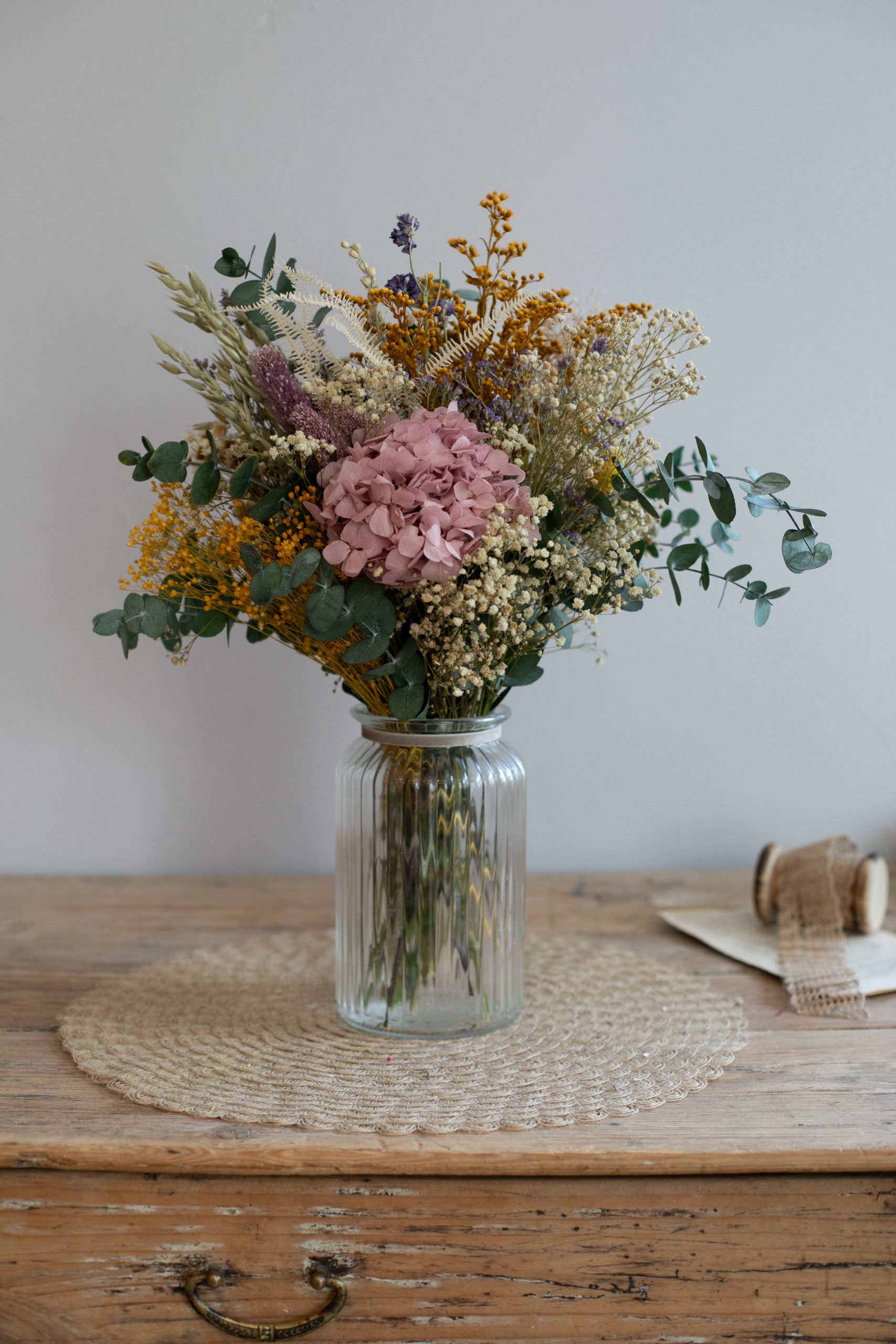 jarrón de cristal con eucalipto hortensia y flores preservadas